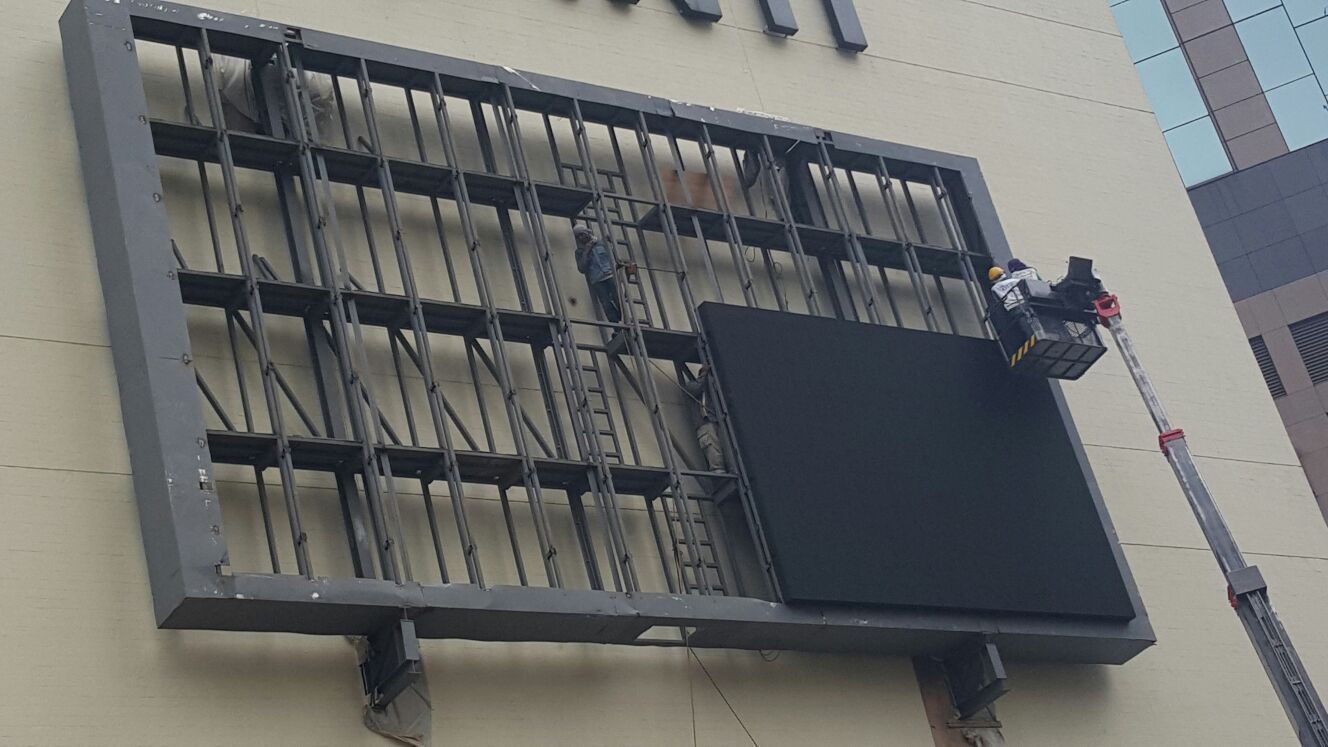 LED cabinet being lifted into its frame by boom lift